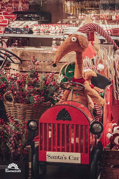 Personnage amusant dans une voiture Santa's Car entouré de décos de Noël